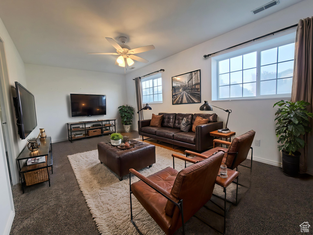 Carpeted living room with a ceiling fan and baseboards