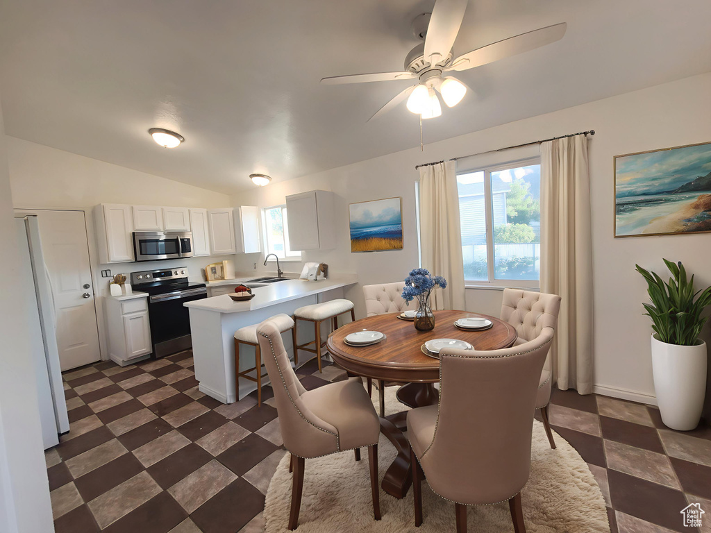 Dining room featuring dark floors, ceiling fan, and lofted ceiling