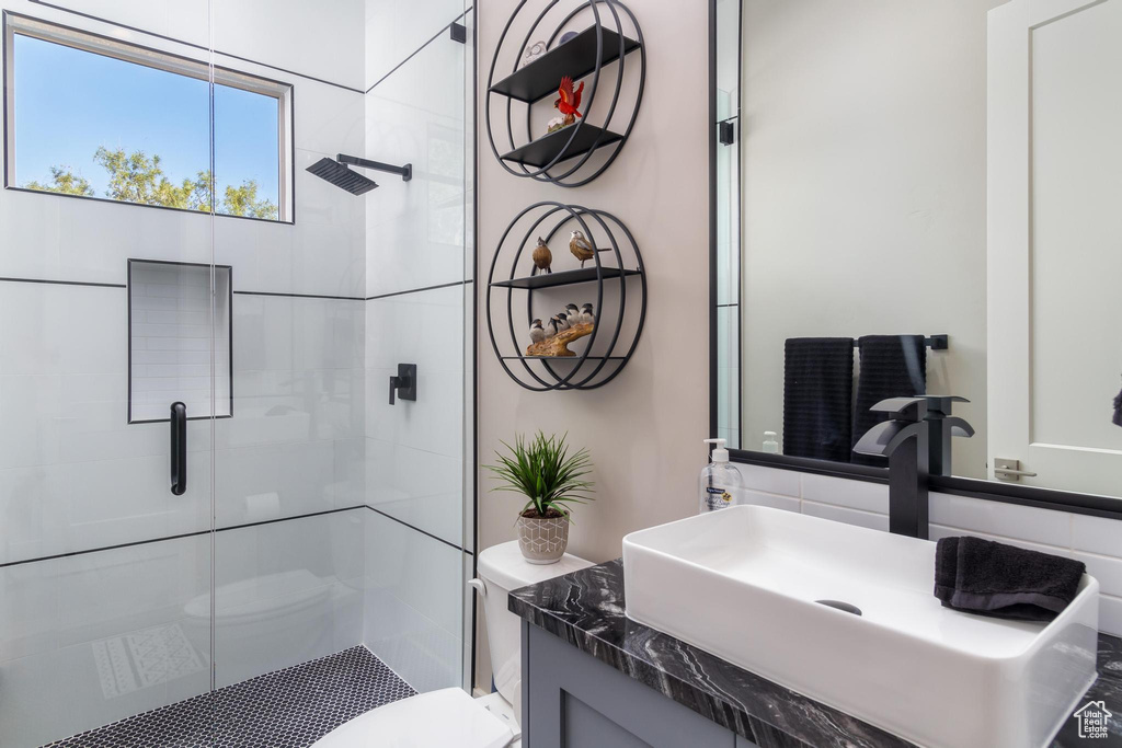 Bathroom featuring vanity, a shower with shower door, and toilet