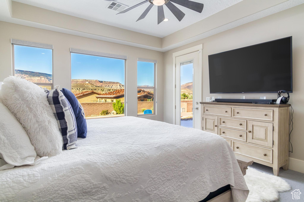 Bedroom with multiple windows, light carpet, and ceiling fan