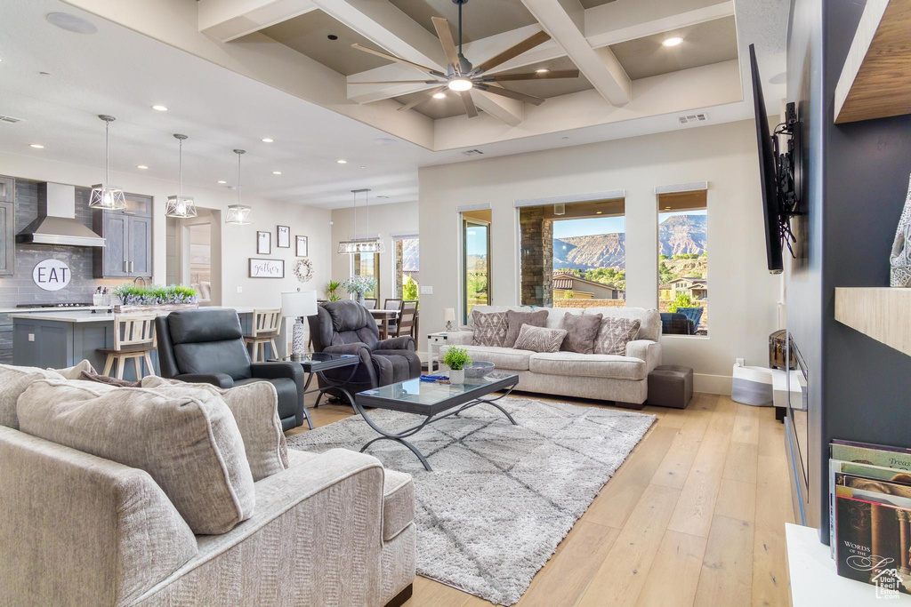 Living room featuring beamed ceiling, ceiling fan, and light hardwood / wood-style flooring