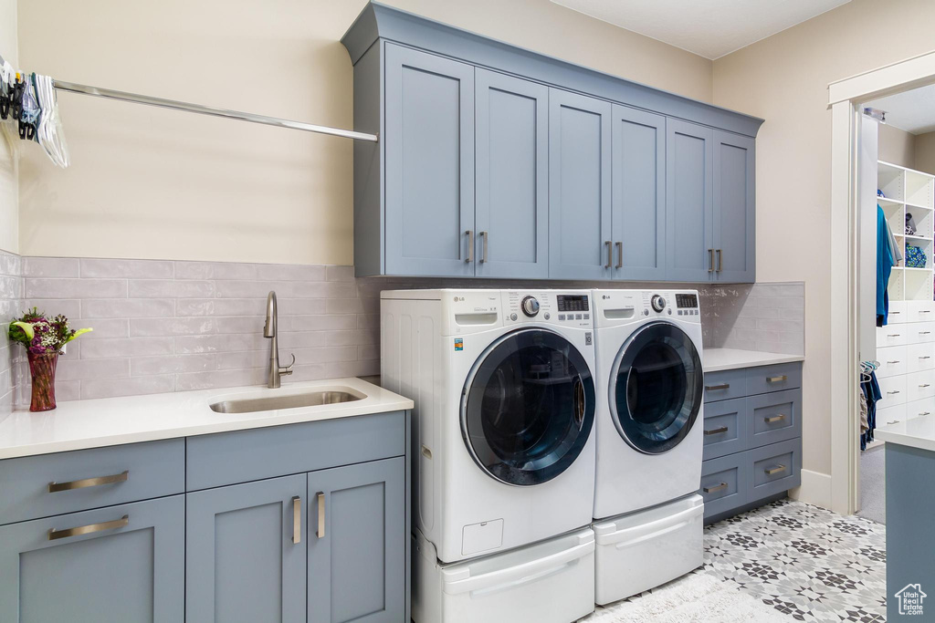 Clothes washing area with cabinets, light tile patterned floors, separate washer and dryer, and sink