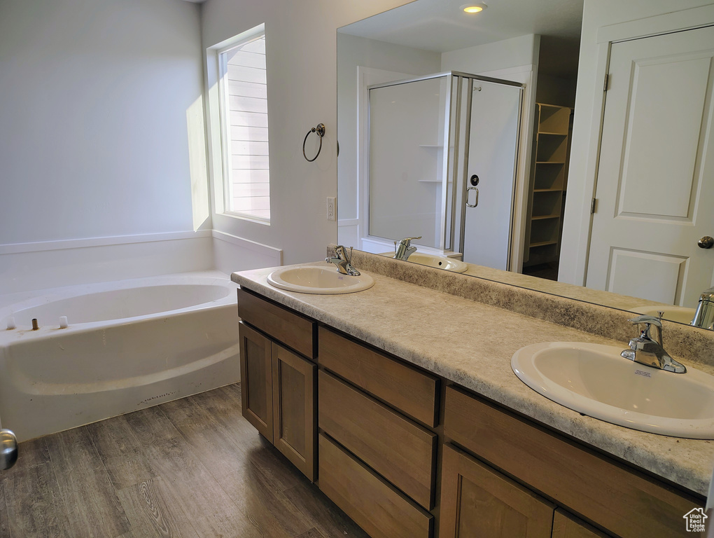 Bathroom with wood-type flooring, vanity, and separate shower and tub