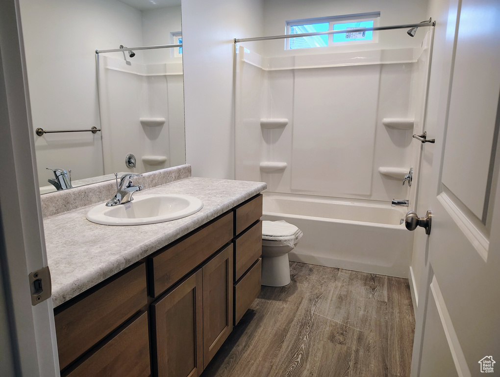 Full bathroom with wood-type flooring, vanity, toilet, and washtub / shower combination