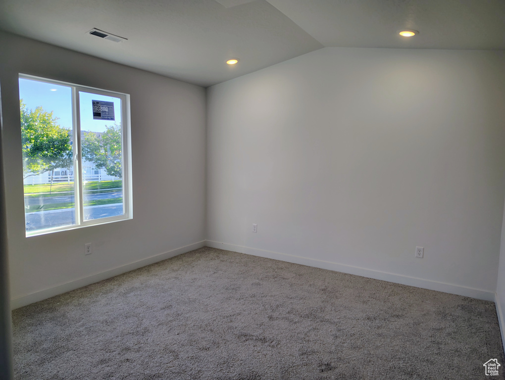 Carpeted spare room with vaulted ceiling