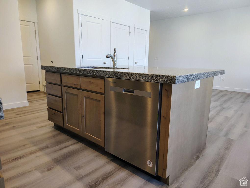 Kitchen featuring dark brown cabinets, dishwasher, sink, light hardwood / wood-style flooring, and a center island with sink