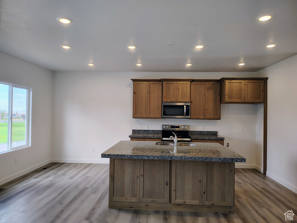 Kitchen featuring an island with sink, appliances with stainless steel finishes, sink, and light hardwood / wood-style floors