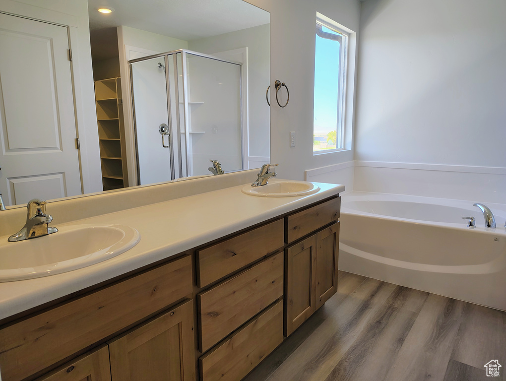 Bathroom with wood-type flooring, vanity, and separate shower and tub