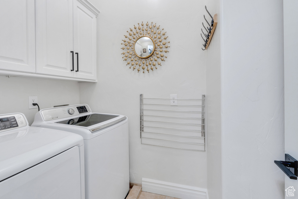 Laundry area with cabinets, light tile patterned floors, and washing machine and clothes dryer