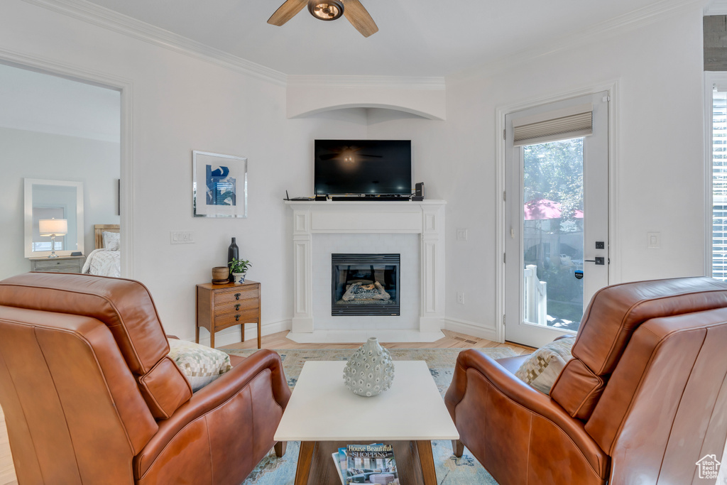 Living room with ornamental molding, light wood-type flooring, and ceiling fan