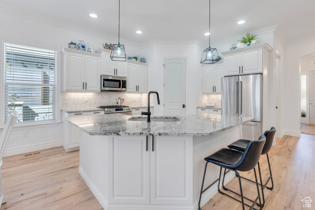 Kitchen featuring pendant lighting, appliances with stainless steel finishes, sink, and white cabinets