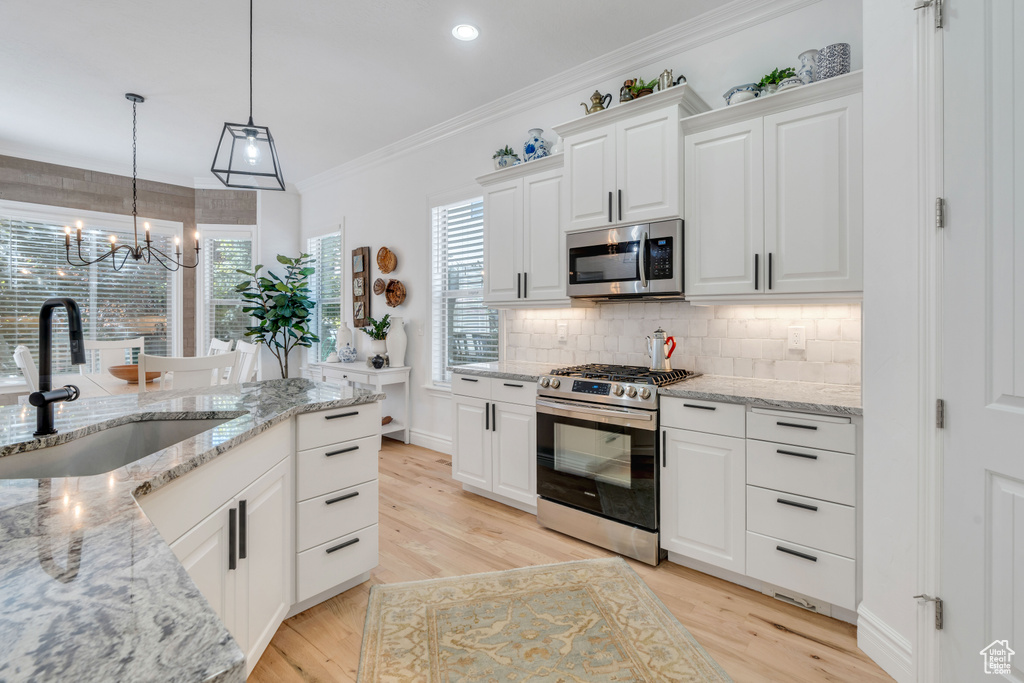 Kitchen featuring light hardwood / wood-style floors, sink, a notable chandelier, white cabinets, and stainless steel appliances