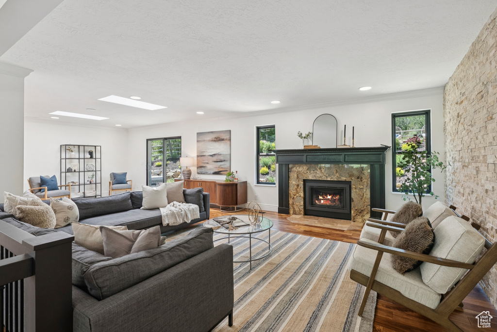 Living room featuring a skylight, light wood-style floors, a high end fireplace, and recessed lighting
