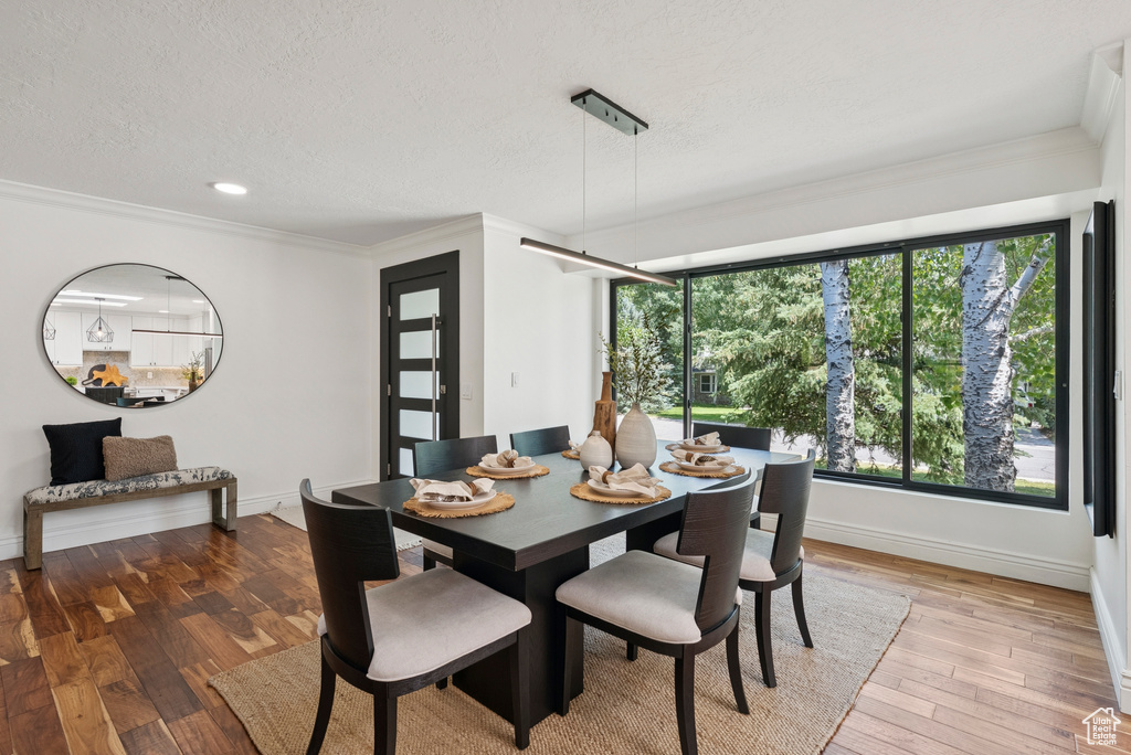 Dining area with crown molding, a textured ceiling, light wood-type flooring, and recessed lighting