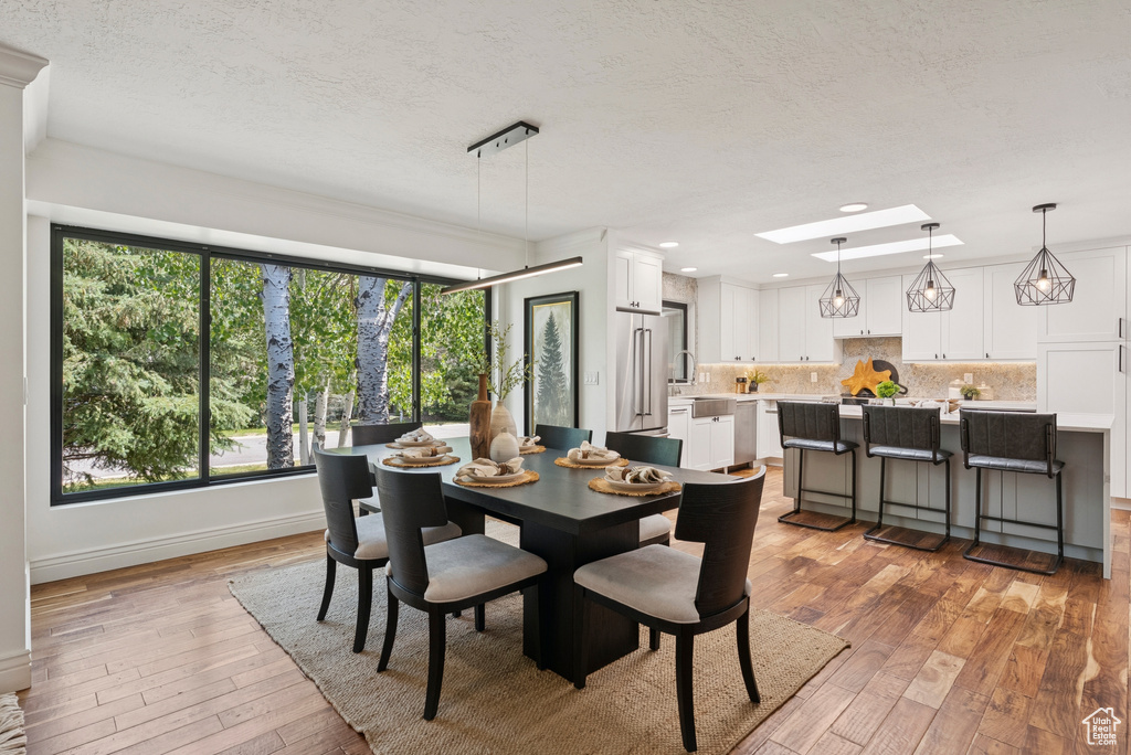 Dining area featuring light wood-style floors, a textured ceiling, and recessed lighting