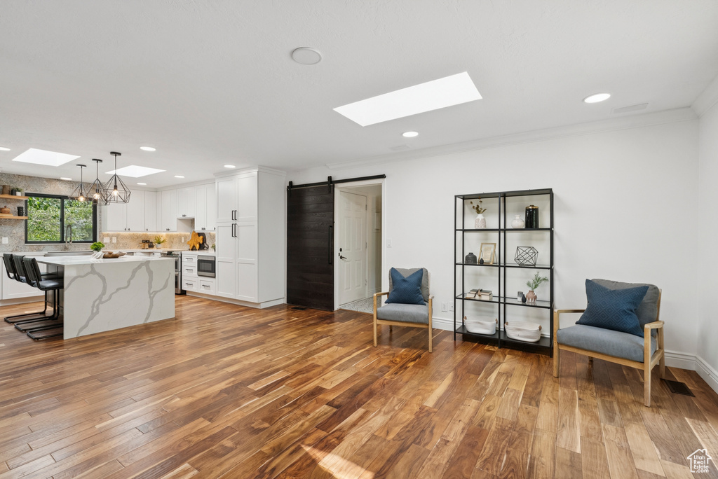 Kitchen with a skylight, light wood-style floors, white cabinetry, crown molding, and recessed lighting