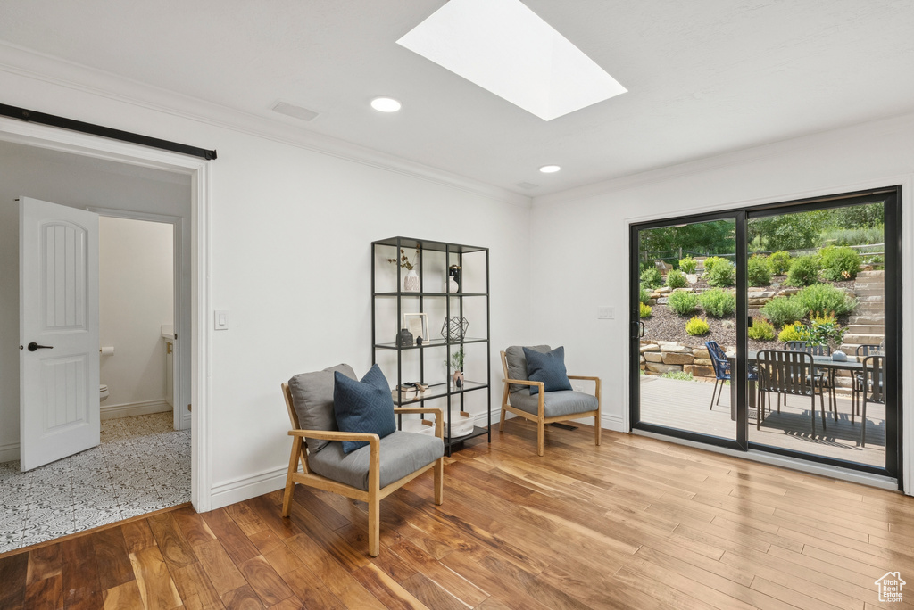 Sitting room with ornamental molding, a skylight, wood finished floors, and recessed lighting