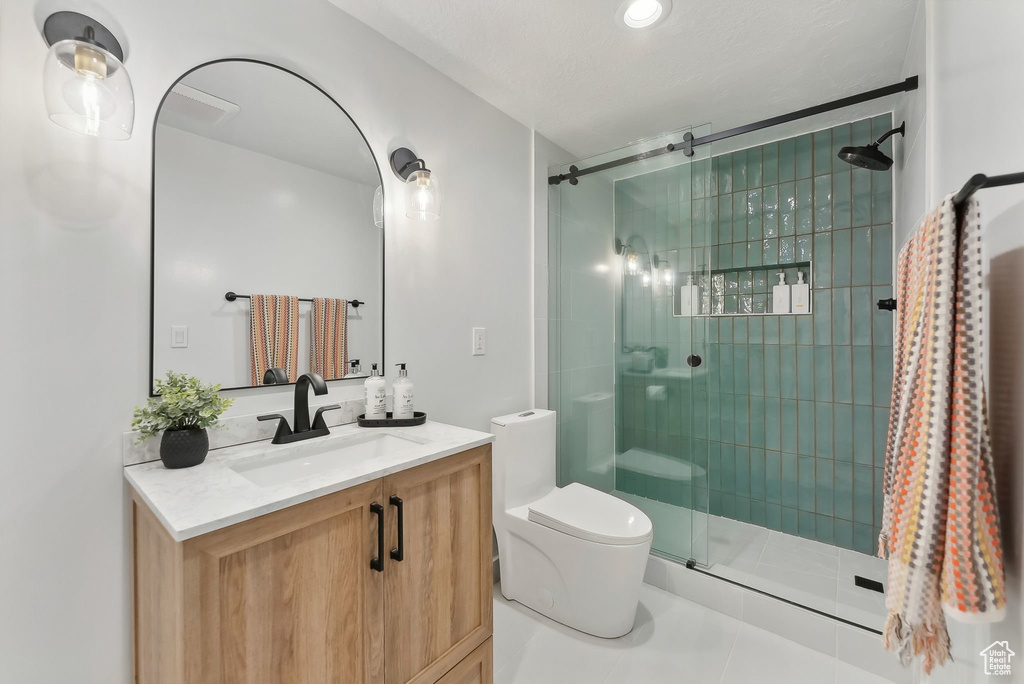 Bathroom featuring tile patterned floors, a shower with door, vanity, and toilet