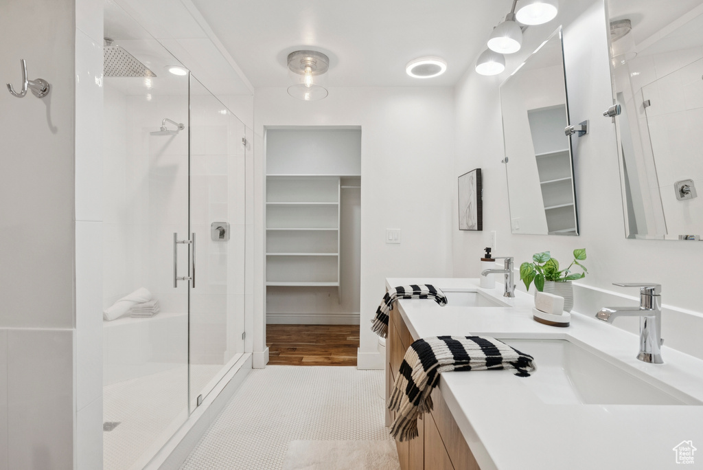 Bathroom featuring a shower stall, double vanity, and a spacious closet