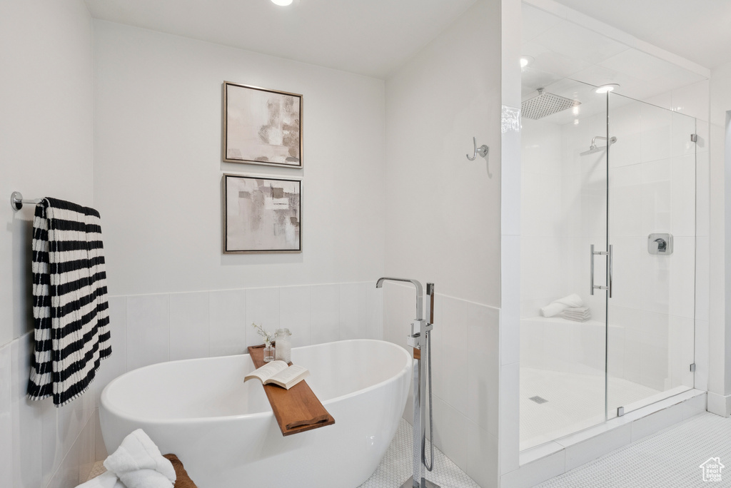 Full bath featuring a shower stall, a freestanding bath, wainscoting, and tile patterned flooring