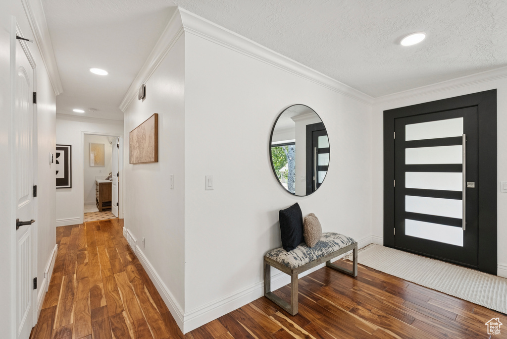 Entryway with ornamental molding, wood finished floors, recessed lighting, and a textured ceiling