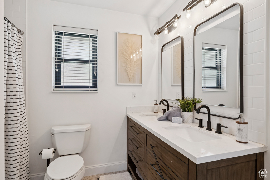 Bathroom with healthy amount of natural light, double vanity, and curtained shower