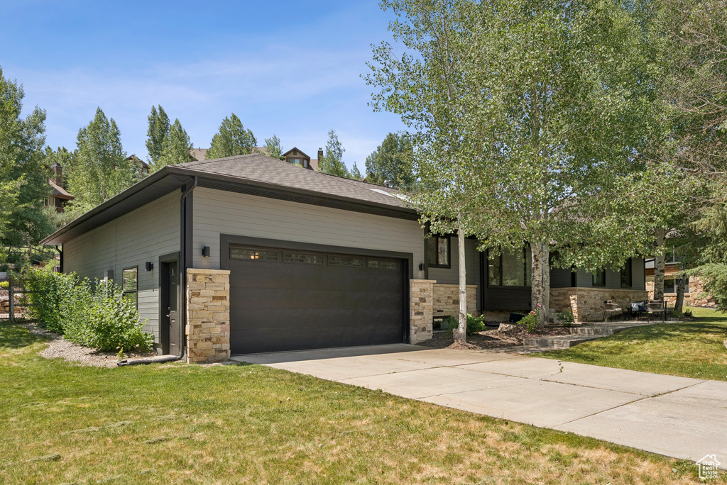 View of front of house featuring an attached garage, driveway, and a front yard