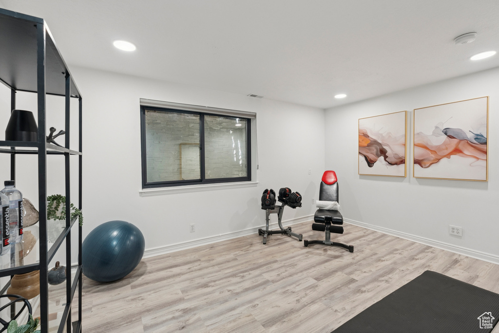 Workout area with light wood finished floors and recessed lighting