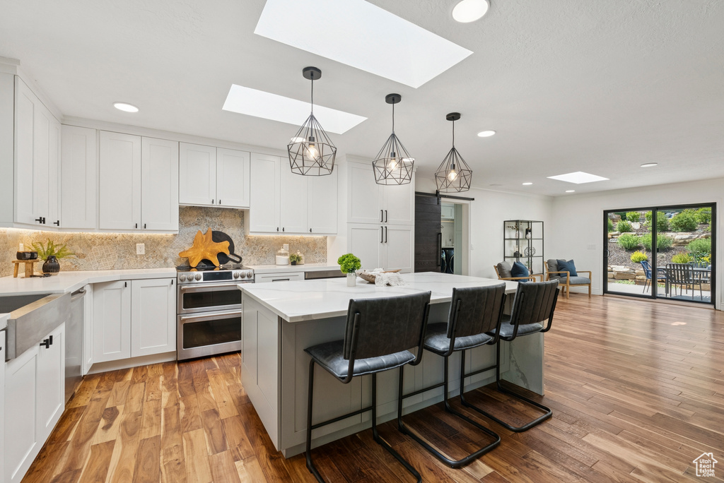 Kitchen featuring appliances with stainless steel finishes, a skylight, a kitchen island, a kitchen bar, and recessed lighting