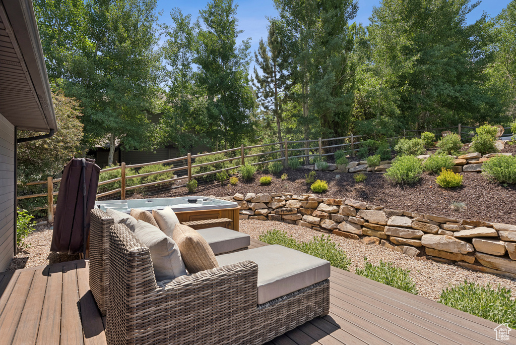 Wooden deck with a hot tub and view of wooded area