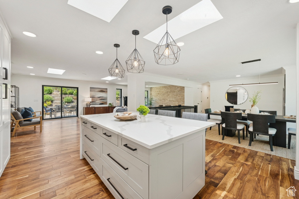 Kitchen with a skylight, open floor plan, recessed lighting, white cabinetry, and hanging light fixtures
