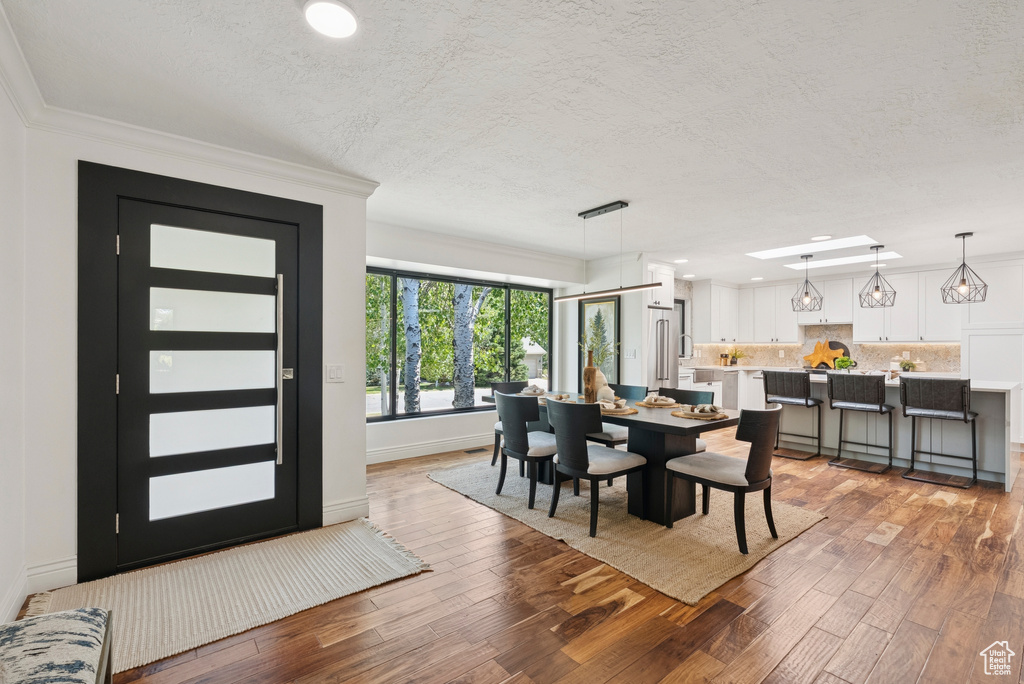 Dining room featuring light wood-style floors, a textured ceiling, ornamental molding, and recessed lighting