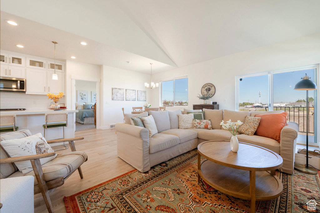 Living room featuring light hardwood / wood-style flooring, a chandelier, and high vaulted ceiling