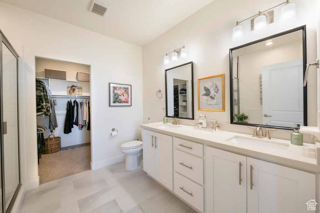 Bathroom featuring vanity, toilet, and an enclosed shower