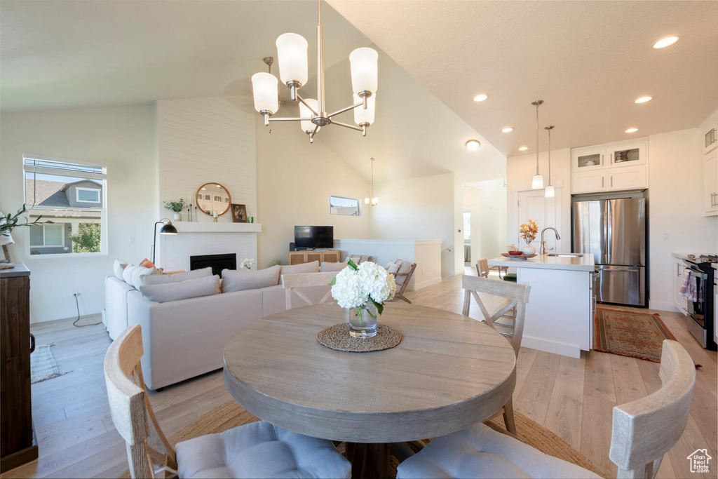 Dining room featuring a notable chandelier, light wood-type flooring, high vaulted ceiling, and sink