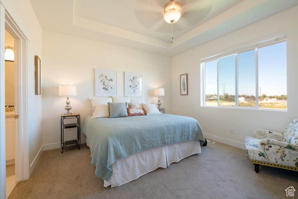 Carpeted bedroom with ceiling fan and a raised ceiling