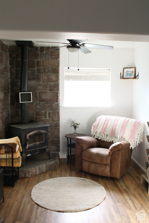 Living room with wood-type flooring, ceiling fan, and a wood stove