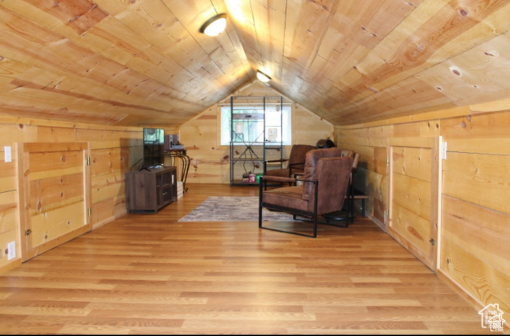 Sitting room with light wood-type flooring, wood walls, lofted ceiling, and wooden ceiling