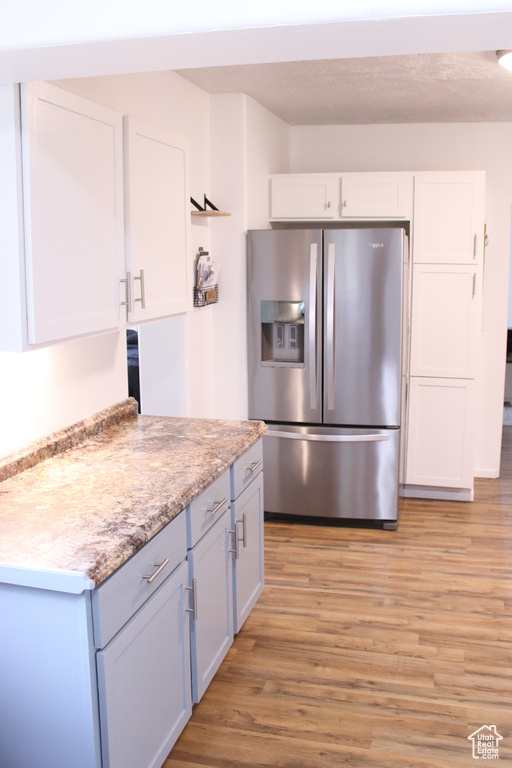 Kitchen featuring light wood-type flooring, white cabinetry, and stainless steel fridge