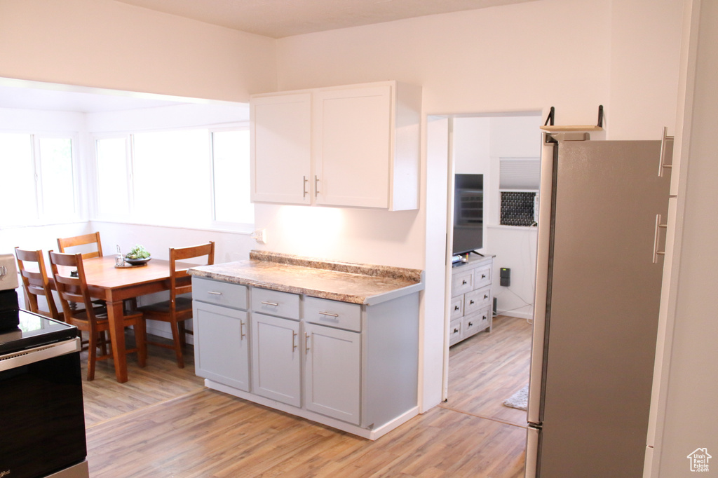 Kitchen featuring a wealth of natural light, light hardwood / wood-style floors, electric range, and stainless steel refrigerator