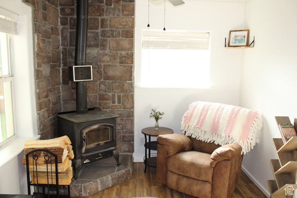 Living area with hardwood / wood-style floors, ceiling fan, and a wood stove