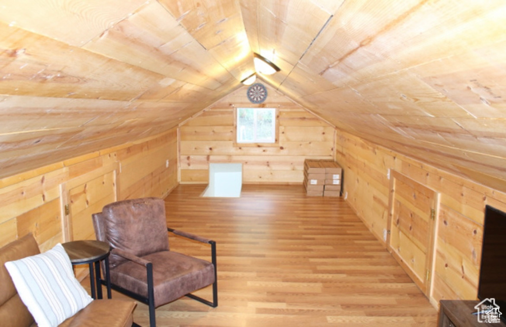 Unfurnished room with wood walls, light hardwood / wood-style floors, wooden ceiling, and lofted ceiling