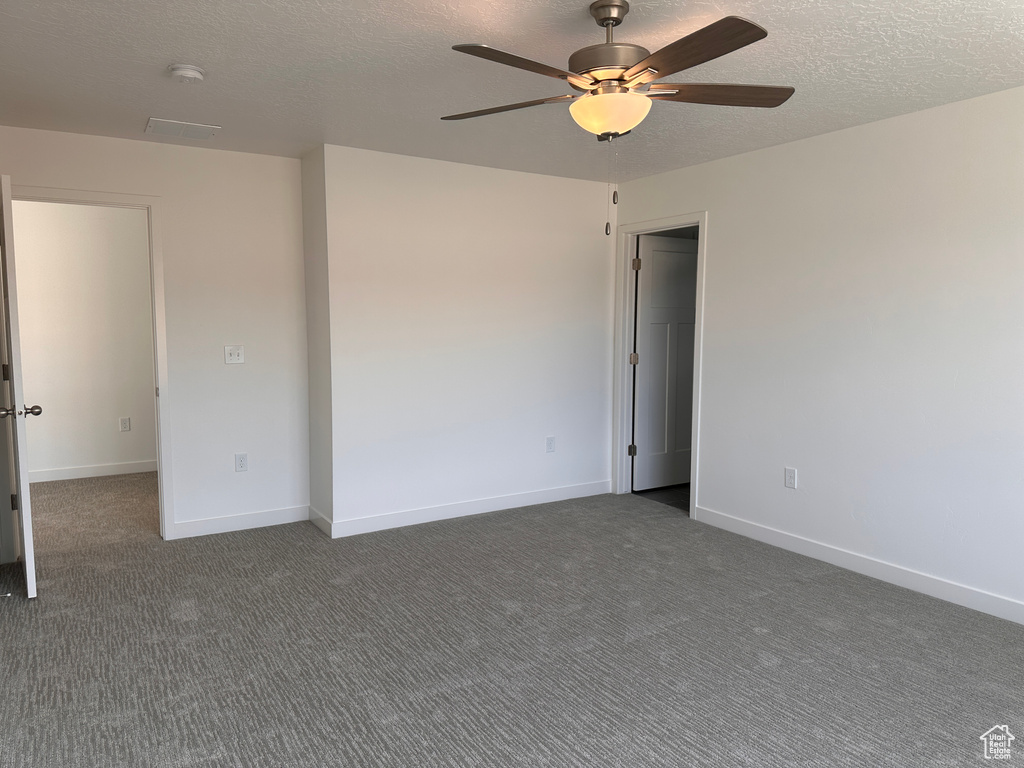 Unfurnished room with ceiling fan, a textured ceiling, and dark carpet