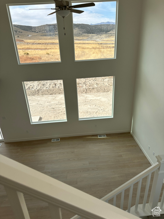 Empty room featuring a mountain view, hardwood / wood-style floors, and a healthy amount of sunlight