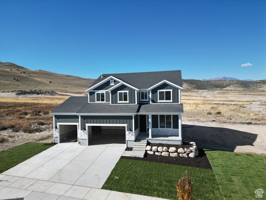 View of front facade with a front yard, a mountain view, and covered porch