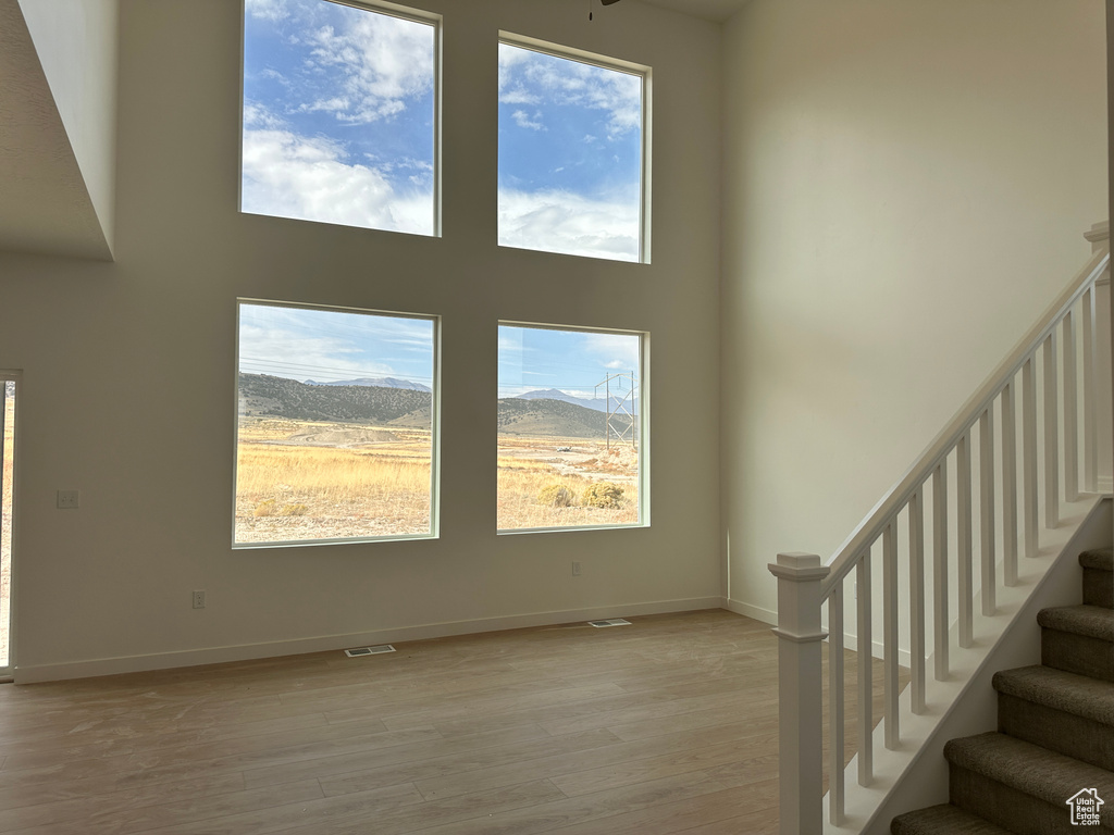 Unfurnished living room featuring a high ceiling, a mountain view, and light hardwood / wood-style flooring