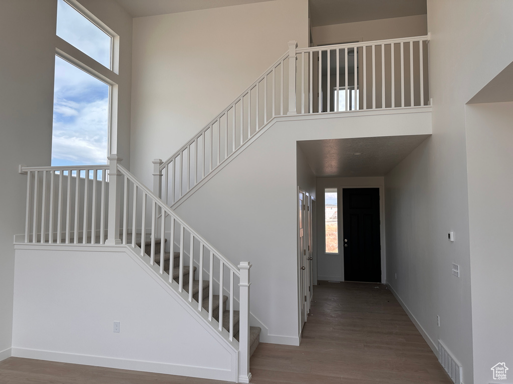 Staircase featuring a high ceiling and hardwood / wood-style flooring