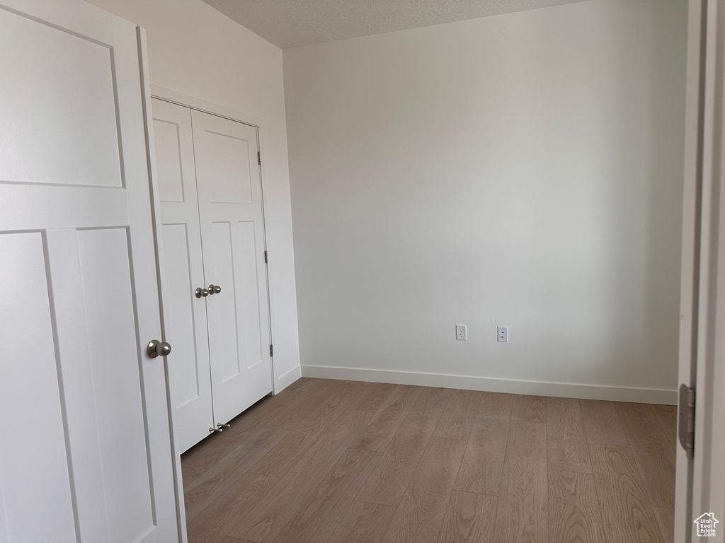 Unfurnished bedroom with light hardwood / wood-style flooring and a textured ceiling