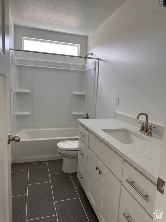 Full bathroom with tile patterned flooring, toilet, shower / washtub combination, vanity, and a textured ceiling