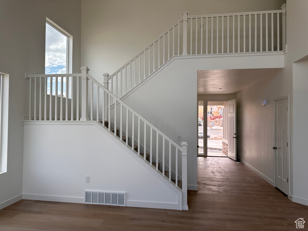 Stairway featuring a high ceiling and hardwood / wood-style flooring